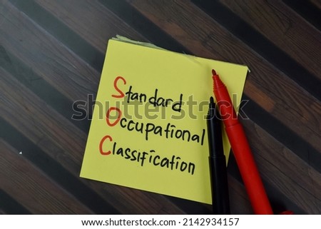 SOC - Standard Occupational Classification write on sticky notes isolated on Wooden Table.