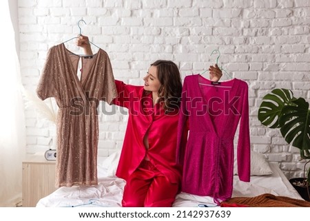 elegant woman in pajamas chooses a dress for a date. Stylish clothes, fashion Royalty-Free Stock Photo #2142937639
