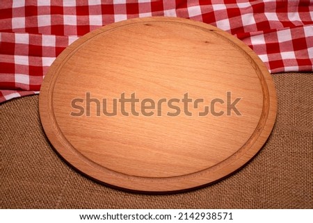 empty pizza board on empty wooden table with tablecloth,napkin - top view