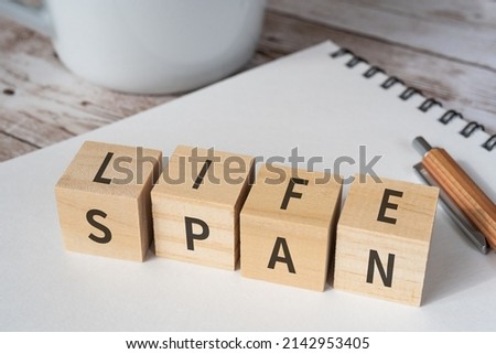 Wooden blocks with "LIFE" and "SPAN" text of concept, a pen, a notebook, and a cup. Royalty-Free Stock Photo #2142953405