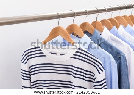Row of sweater with long sleeved blue and striped shirts ,blue ,white on hanger