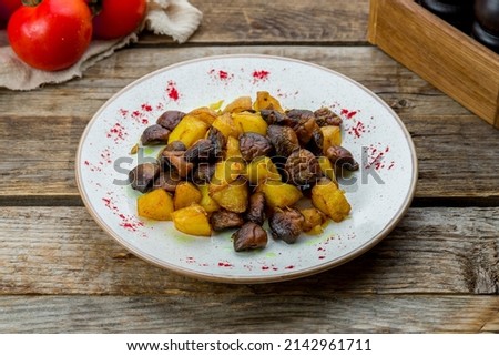 Fried potatoes with mushrooms on plate on old wooden table