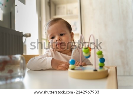 A baby girl is playing in her room during the day