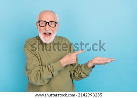 Portrait of attractive cheerful amazed grey-haired man demonstrating offer ad isolated over bright blue color background