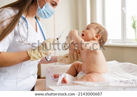 Young female pediatrician vaccinates a little baby boy Immunization for children concept. Happy little cute boy getting a flu shot not afraid of the syringe needle. Doctor injecting brave child with Royalty-Free Stock Photo #2143000687