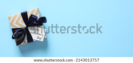 Happy Fathers day concept. Flat lay vintage gift box with blue ribbon bow and label Happy Father's day on color background. Fathers day wide banner design. Royalty-Free Stock Photo #2143013757