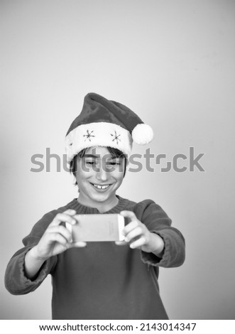 Young boy wearing Christmas hat taking selfie on a white background