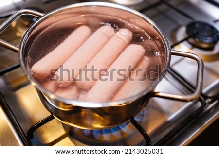 sausages in boiling water in a saucepan on the burner of the gas stove. preparation of semi-finished products for lunch. simple meals for every day. 