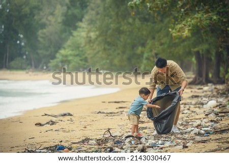 Asian father and son of volunteer people collecting trash on beach. Ecology charity and clean environment earth day concept. Royalty-Free Stock Photo #2143030467
