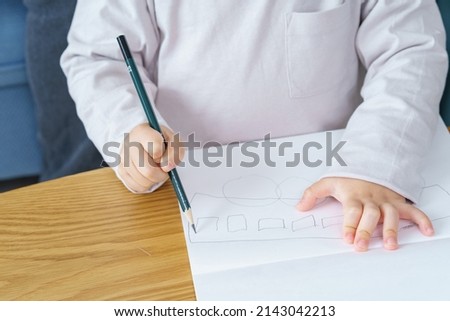 A boy working on drawing with a pencil and his parents watching over it