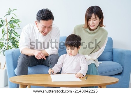 A boy working on drawing with a pencil and his parents watching over it