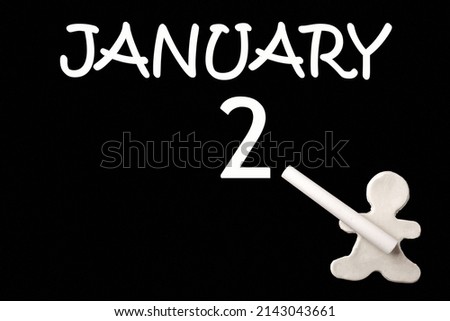 2nd day of January. A small white plasticine man writing the date 2 January on a black board. Business concept. Education concept. Winter month, day of the year concept.