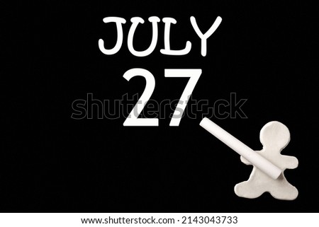 27th day ofJuly. A small white plasticine man writing the date 27July on a black board. Business concept. Education concept. Summer month, day of the year concept.