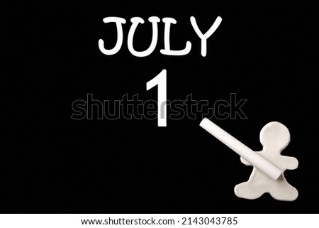 1st day ofJuly. A small white plasticine man writing the date 1July on a black board. Business concept. Education concept. Summer month, day of the year concept.