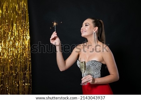 woman at a holiday party with a glass of champagne and a sparkler