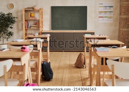 Wide angle background image of wooden school desks in row facing blackboard in empty classroom, copy space Royalty-Free Stock Photo #2143046563