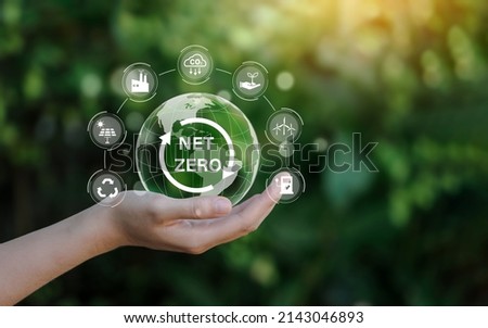 Net zero icon and carbon neutral concept in the hand for net zero greenhouse gas emissions target Climate neutral long term strategy on a green background. Royalty-Free Stock Photo #2143046893