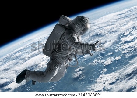 Caucasian female astronaut using her mobile phone during spacewalk near planet Earth, messaging, taking pictures Royalty-Free Stock Photo #2143063891
