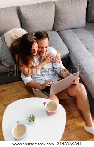 High angle view of beautiful couple in love having video call with friends using laptop computer at home