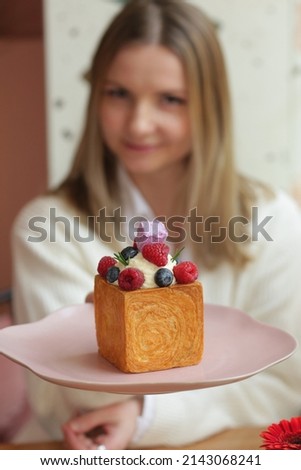 blond girl with cube formed dessert with cream, raspberry, blueberry and marshmallow topping close up photo 