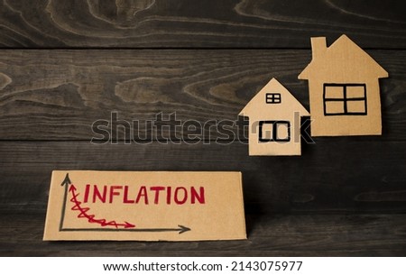 On a wooden background, the inscription on the cardboard inflation and models of houses.  The concept of inflation in the change in housing prices, increasing the interest rate on mortgages. 