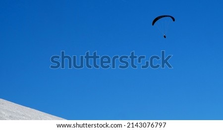 parapenting high above the snowy mountains in austria