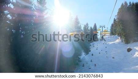 chairlift with snow and trees underneath the blue sunny sky