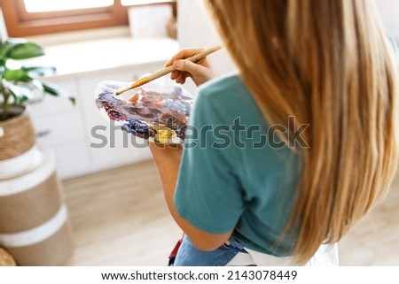 Fine art school. Closeup of artist portrait ,hands holding wooden palette, mixing acrylic paint with brush.Artist woman with paint palette.Hand with brush painting. 