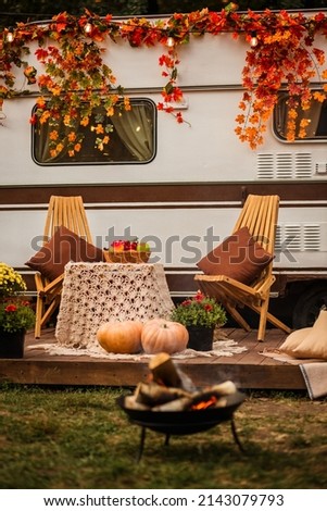 kindled a fire in front of the trailer. Camping autumn. Trailer on the background of the forest