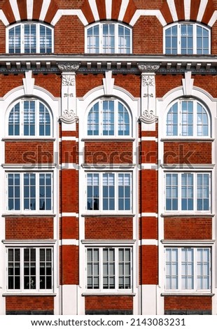 Architectural detail of Victorian building, with red brick, arched windows and decorative plaster work in Art Nouveau style. Geometric background image.