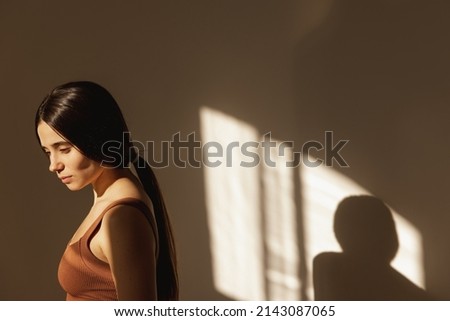 Cute caucasian young teenage girl looking down on background with space for text. Woman with dark frizzy hair in brown top. Sunny summer holiday concept