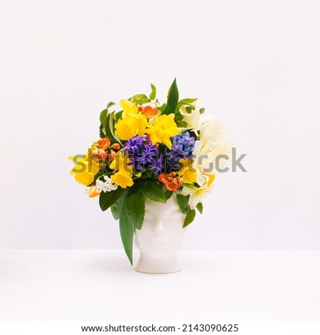 Fresh bunch of colorful flowers in human head shaped vase on white background. Card Concept, copy space for text. Creativity, nature, ecology and springtime concept.