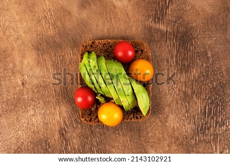 Sandwich or toast on the wooden background. Toast with avocado, cherry tomatoes and almond. Vegetarian and vegan food.