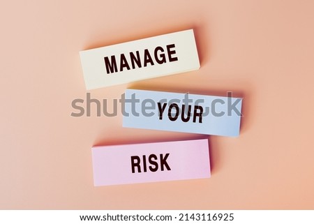 Manage Your Risk. Concept of text on color cards. Top view image of cards and on pastel beige background. Flat lay design