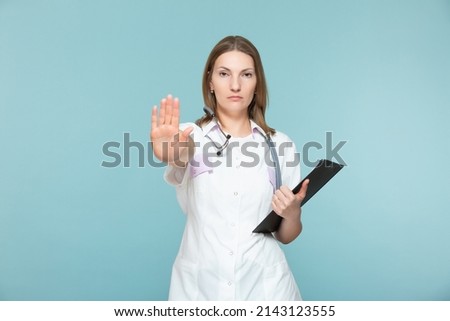 Beautiful woman doctor with a stethoscope and a black tablet, shows a stop sign with her hand, on a blue background. Copy paste. healthcare concept. Let's stop the disease.