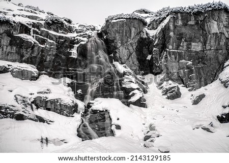 Long exposure shot of water in mountain at winter. Black and white photography. Waterfall Skok in High Tatras mountains, Slovakia.