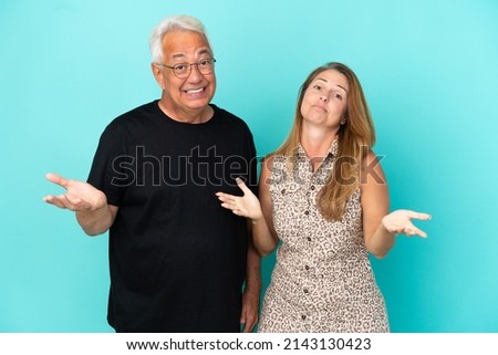 Middle age couple isolated on blue background unhappy and frustrated with something because not understand something Royalty-Free Stock Photo #2143130423