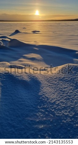 the sun over the snow-covered  of the Karelian lake in winter