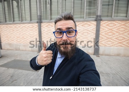 Mid adult man taking selfie and showing thumb up outdoors