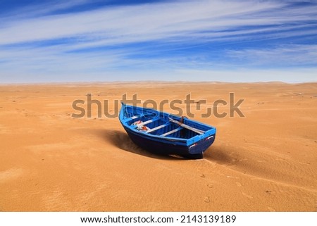 Morocco landscape. Lone blue fishing boat in the desert sand near Essaouira beach. Royalty-Free Stock Photo #2143139189