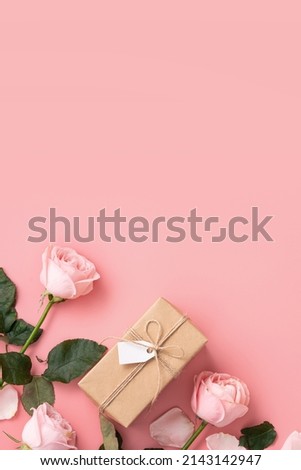 Mother's Day design concept background with pink rose flower and wrapped kraft gift box on pink table background.