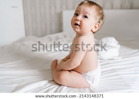 Infant baby kid sitting back happy smiling sitting on white bed at home Royalty-Free Stock Photo #2143148371