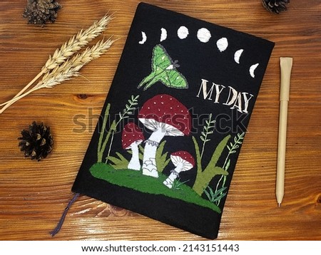 A notebook in a black paperback with mushrooms, moon phases and moths, handmade stationery, an original gift in the goblincore style
