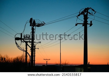 Electric poles with power lines at sunset. Electricity transmission. Royalty-Free Stock Photo #2143155817
