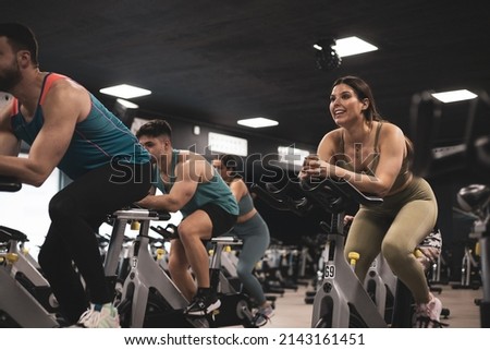people on bikes in spinning class in modern gym, exercising on stationary bike. group of athletes training on exercise bike Royalty-Free Stock Photo #2143161451