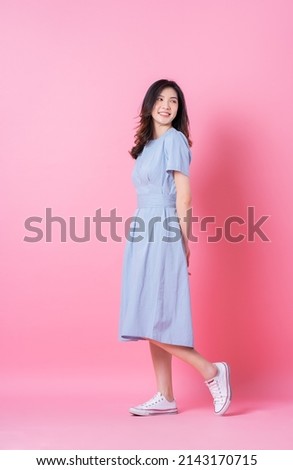 Full length image of young Asian woman wearing blue dress on pink background Royalty-Free Stock Photo #2143170715