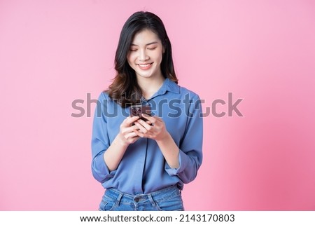 Image of young Asian business woman using smartphone on pink background
