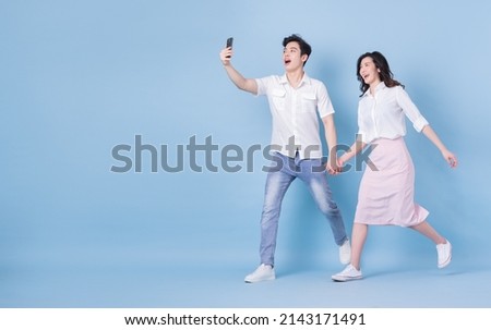 Full length image of young Asian couple on blue background Royalty-Free Stock Photo #2143171491