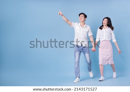 Full length image of young Asian couple on blue background