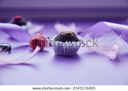 Chocolate festive candy with nuts and pink rose. Trendy pink feathers and purple ribbon. Very peri pantone color pattern